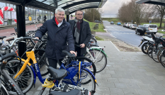Gedeputeerde Andre van Schie en wethouder Joop van Montfoort van gemeente Vijfheerenlanden stallen hun fietsen in de nieuwe overdekte fietsenstalling. 