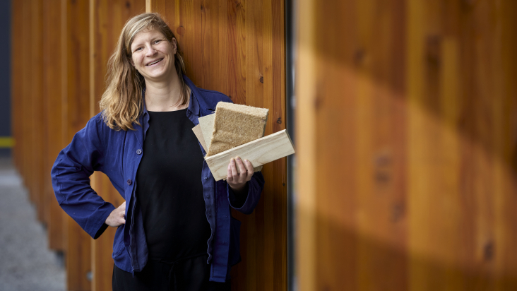 Nienke Binnendijk met biobased materiaal en biobased huis op achtergrond